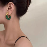 The earrings displayed on a luxurious velvet backdrop, emphasizing their Parisian chic style.