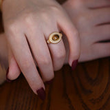 Lifestyle image of a woman adjusting her resizable Tiger Eye ring to fit perfectly while sitting in a café