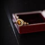 Resizable Tiger Eye Masterpiece Ring for women on a dark, reflective surface, emphasizing the gem's brilliance and band's flexibility
