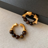 A close-up shot of the earrings, showcasing the intricate design and the rich, golden hues of the tiger eye gemstones.